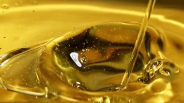 Bir zeytin yağı püskürtüsü dalgalar ve sıçramalarla akar. Makro arka plan. 1000 fps hızla yüksek hızlı bir kamerayla çekildi.. 