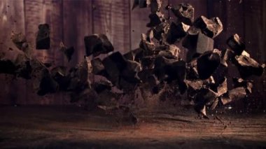 Masaya bir çukulata yığını düşüyor. Ahşap bir arka planda. Film yavaş çekimde 1000 fp.. 