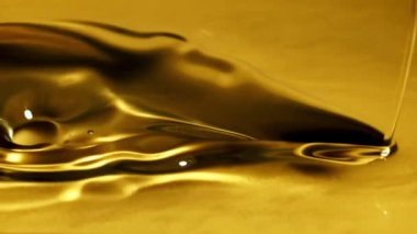 Bir zeytin yağı püskürtüsü dalgalar ve sıçramalarla akar. Makro arka plan. 1000 fps hızla yüksek hızlı bir kamerayla çekildi.. 