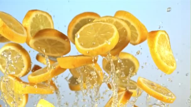 水のレモンの一片が飛んで落ちます 青い背景で 撮影はスローモーション1000 Fps — ストック動画