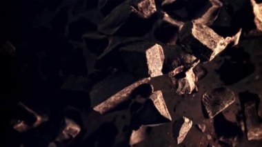 Çikolata parçaları uçar ve düşer. Karanlık bir arka plana karşı. Film yavaş çekimde 1000 fp.. 