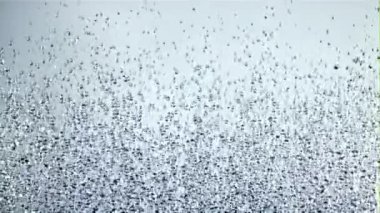 Su damlacıkları yükselir ve düşer. Beyaz bir arka planda. Film yavaş çekimde 1000 fp..