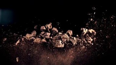 Bir yığın çikolata parçası yükselir ve düşer. Siyah bir arka planda. Film yavaş çekimde 1000 fp..
