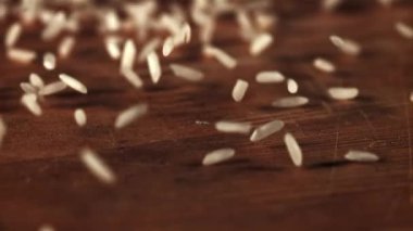 Çiğ pirinç masaya saçılmış ve döndürülmüştür. Tahta bir arka planda. 1000 fp 'lik yüksek hızlı bir kamerayla çekildi..