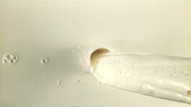 Taze süt su sıçramaları ve hava kabarcıklarıyla bir derede akar. Makro arka plan. 1000 fps hızla yüksek hızlı bir kamerayla çekildi..