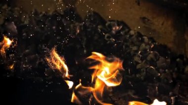 Kömürler fırında alevli bir ateş topuyla karıştırılıyor. Siyah bir arka planda. 1000 fps hızla yüksek hızlı bir kamerayla çekildi..