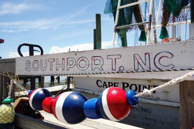 Yıpranmış bir Southport, NC işareti Cape Fear Nehri 'ndeki bir balıkçı teknesinin önünde asılı duruyor.