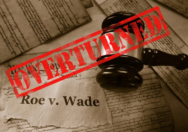 Roe v Wade news headline with gavel and Overturned stamp on a copy of the United States Constitution