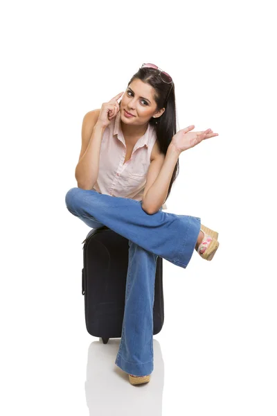 Young woman sitting on suitcase — Stock Photo, Image