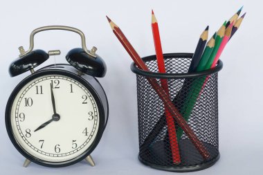 Masada renkli kalemler olan çalar saat.