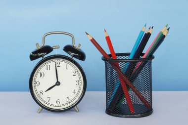 Masada renkli kalemler olan çalar saat.