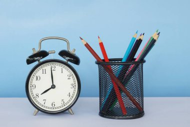 Masada renkli kalemler olan çalar saat.