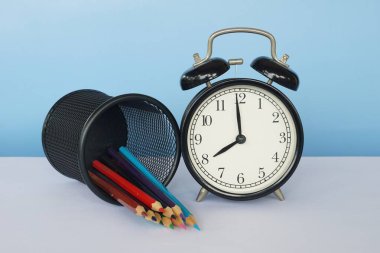 Masada renkli kalemler olan çalar saat.