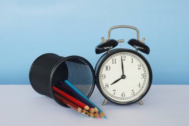 Masada renkli kalemler olan çalar saat.