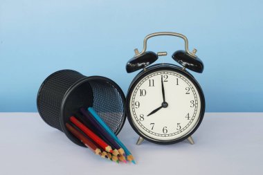 Masada renkli kalemler olan çalar saat.