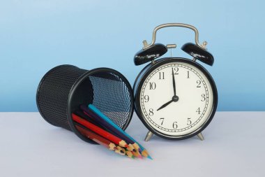 Masada renkli kalemler olan çalar saat.