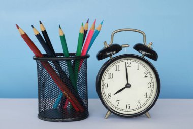 Masada renkli kalemler olan çalar saat.