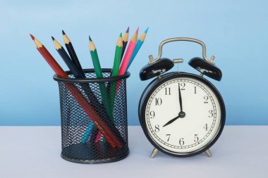 Masada renkli kalemler olan çalar saat.