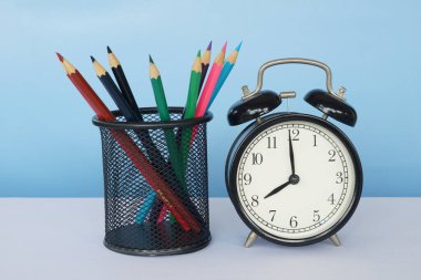 Masada renkli kalemler olan çalar saat.