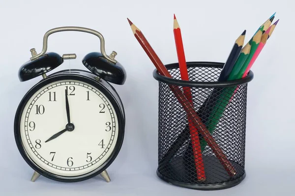 Masada renkli kalemler olan çalar saat.