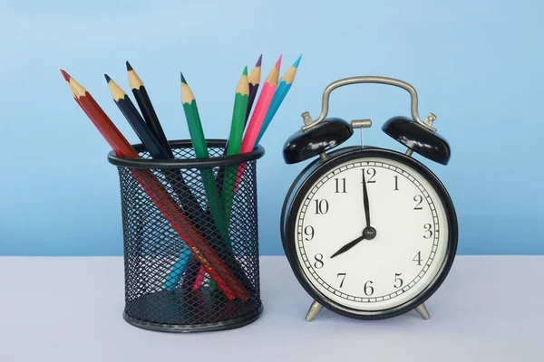 Masada renkli kalemler olan çalar saat.