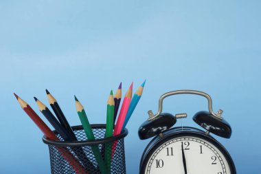 Masada renkli kalemler olan çalar saat.