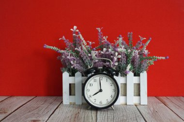 Çalar saat ve saksı çiçeği masanın üstünde.