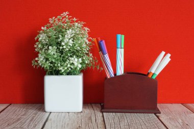 Çiçek saksısı ve kalemler masanın üstünde.