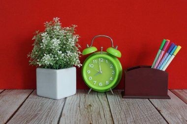 yeşil alarm saati ve kalemler masada.