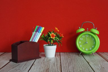 Çalar saat. Masada renkli kalemler var.