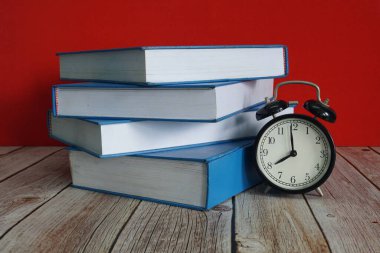 Kitaplar ve çalar saat masanın üstünde.