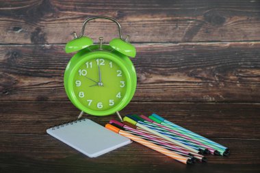 Masadaki çalar saat ve kalemler.