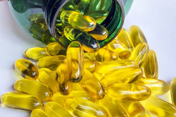 Gelbe Pillen vor der grünen Flasche — Stockfoto