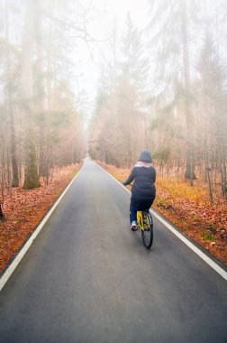 Sonbahar sisli parkında bisiklet süren kız..