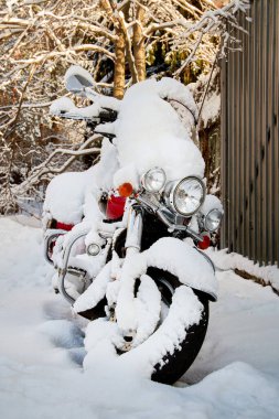 Evin bahçesindeki karın altında motosiklet..
