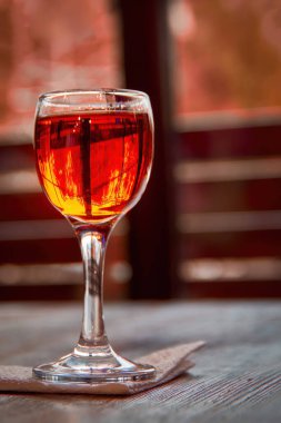 Glass of cognac on wooden table. Shot glass on the background of a window