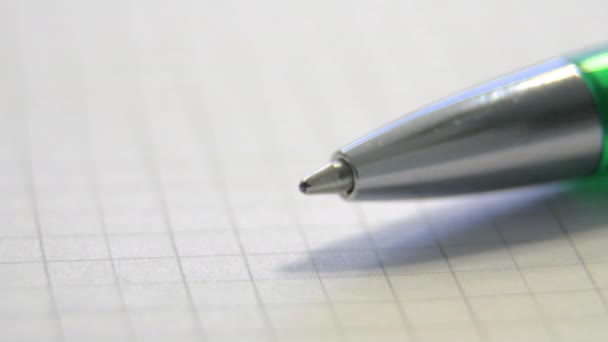 Зеленая шариковая ручка на клетчатом листе бумаги — стоковое видео