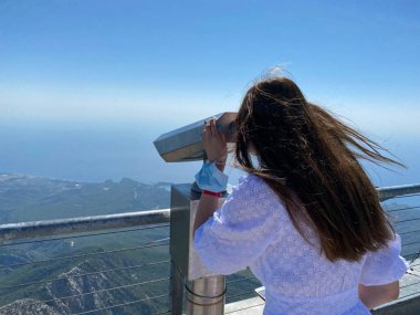 Parlak sırt çantalı hippi genç kız gözlem güvertesine bakıyor ve seyahat planı yapıyor. Turistin arkasından bak..