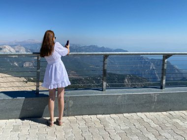 Genç bir kadın güvertede oturuyor ve doğaya bakıyor..