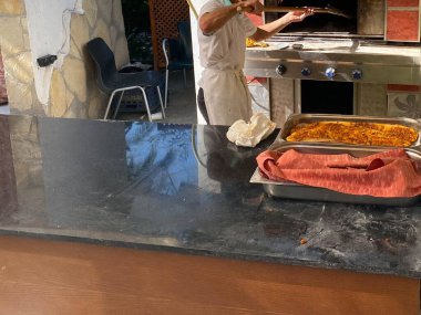 Önlüklü erkek pizza yapıyor ve fırına koyuyor..