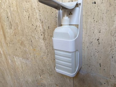 Corona salgını sırasında hastanenin duvarında asılı duran bir şişe dezenfektan jeli. Antibakteriyel jel insanların ellerini dezenfekte etmek için kullanılır..