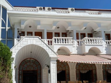 Balkonları ve terasları olan, otelin içinde tropik bir tatil köyüne giriş yapan güzel beyaz klasik bir bina..