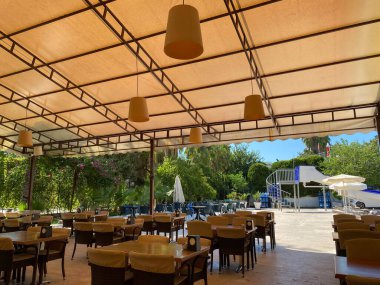 Bir barı olan açık bir kafe masası ahşap masa ve sandalyeler ile bir açık veranda bir dinlenme tatil palmiye ağaçları ile tropikal bir sıcak ülkede sokakta bulunmaktadır.