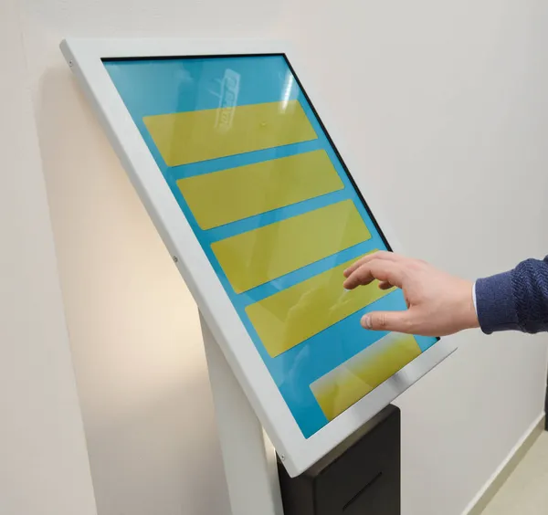 Man orders food in the touch screen terminal with electronic menu in fastfood restaurant. Modern technology concept.