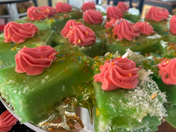 結婚式のレセプションでピンク色の甘いクリームがトッピングされた木製のプレート上の多くの緑茶ケーキ — ストック写真