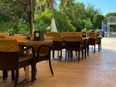 Açık hava masalarının güzel manzarası. Mavi sandalyeler ve yeşil palmiye ağaçları ve mavi gökyüzü arka planında turuncu şemsiyeler. Key West, Florida. Usa.