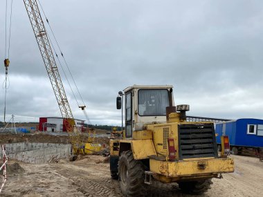 Birçok araba, kazıcı, kamyon, yükleyici, beton karıştırıcı ve inşaat makineleri sanayi bölgesindeki büyük otoparkta, beton ve asfalt fabrikasının yanında..