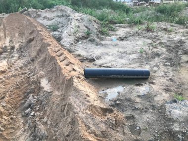 İnşaat alanındaki toprak. Traktörlerden ve kaldırımlardan kum izlerine. Kum izleri, ağır araçların izleri. Yakınlarda evler için iletişim sağlayan plastik bir boru var..