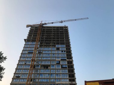 Uzun, yeni, beton bloklu cam bir bina. Panoramik pencereli yeni bir ev. İnsanların ve ailelerin hayatı için bir ev inşa ediliyor. Şehir merkezinde güzel ve modern bir bölge..