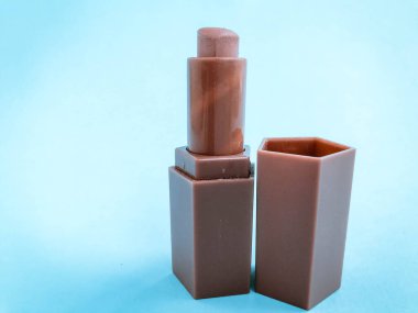 Mavi, parlak bir arka planda mat ruj izi. kalp şeklinde bej ruj, yumuşak kahverengi ton. Çıplak, güzel dudak makyajı..